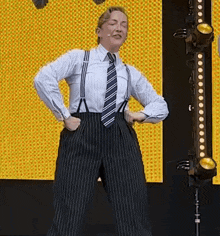 a man wearing suspenders and a tie is dancing on stage .