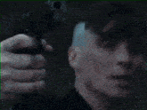 a man in a suit and tie is holding a gun in a dark room .