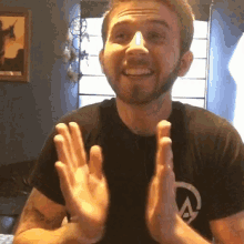 a man with a beard wearing a black t-shirt with the letter a on it