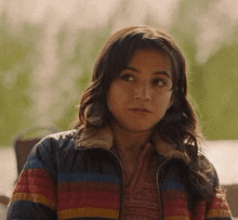 a young woman wearing a striped jacket looks at the camera .