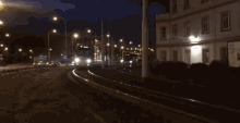 a bus is driving down a street at night with a building in the background .