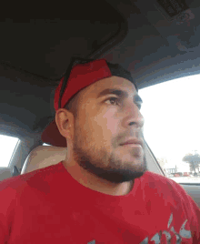 a man wearing a red shirt and a red hat looks at the camera
