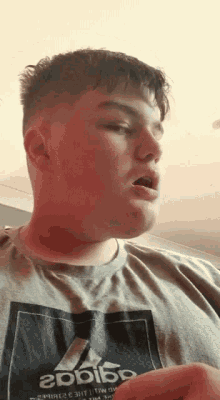 a man wearing an adidas t-shirt is making a face