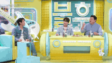 three men are sitting at a table in front of a sign that says ' korean ' on it