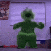 a person in a green inflatable dinosaur costume is standing in a room .