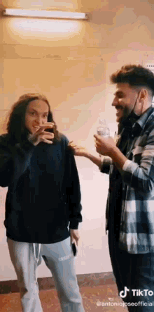 two men are standing next to each other in a room and talking .