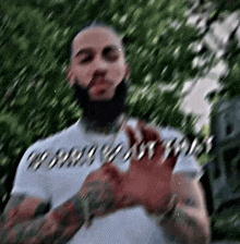 a man with a beard and tattoos is wearing a white shirt and holding a piece of paper .