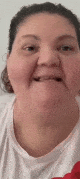 a close up of a woman making a funny face while wearing a white t-shirt .