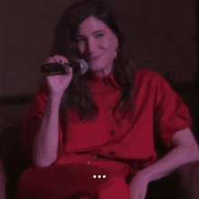 a woman in a red shirt is holding a microphone and the word anyway is on the bottom right
