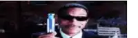 a man wearing sunglasses and a hat is holding a can of beer in his hand .