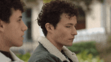 two young men are standing next to each other and one has curly hair