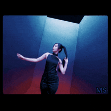 a woman in a black dress is standing in a dark room with the letters ms on the bottom right