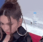 a woman wearing hoop earrings and a bun is sitting next to a bottle of water .