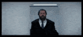 a man with a beard wearing a black suit and tie