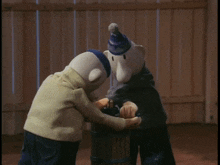 two stuffed animals are standing next to each other and one is wearing a blue hat