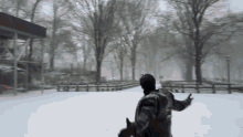 a man in a black jacket is standing in a snowy park