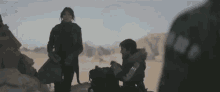 a couple of people standing next to each other in a desert .