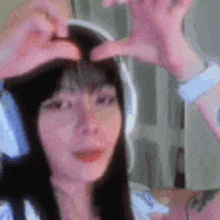 a woman wearing headphones and making a heart with her hands .
