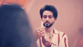 a man with a beard and a necklace is holding a white object