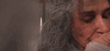 a woman with gray hair is talking on a cell phone while looking at herself in the mirror .