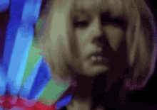 a close up of a woman 's face with a rainbow of colors in the background