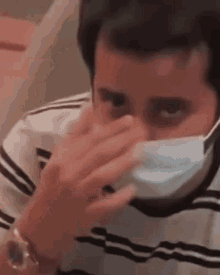 a man is wearing a face mask and covering his nose .