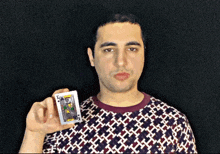 a man in a patterned shirt is holding a joker card in his hand