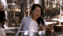 a woman sitting at a table with a cup of coffee and a pine cone says i have mixed feelings