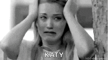 a black and white photo of a woman holding her head with the word katy written on it .