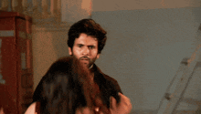a man with a beard is holding a woman 's arm