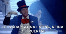 a man in a top hat and bow tie is standing on stairs and talking in spanish .