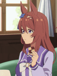 a girl in a purple uniform holds a piece of chocolate in her hand