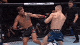 two men are fighting in a cage and one has a venum shorts on