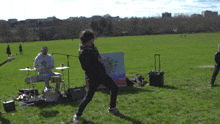 a man playing a guitar in a park with a drummer
