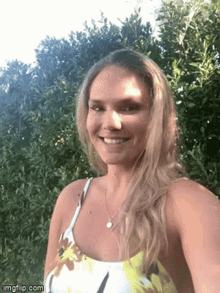 a woman is taking a selfie in front of some trees and smiling