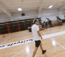 a man walking on a basketball court with the word barych written on the floor