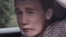 a young man is crying in a car while sitting in the back seat .