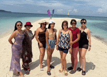a group of women posing for a picture on a sandy beach