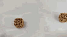 a person is holding two gold beads in their hands .