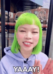 a woman with green hair says yaaay in front of a window