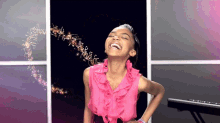 a girl in a pink ruffled top is laughing in front of a piano keyboard
