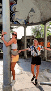 two women standing next to each other with one wearing a shirt with the letter r on it