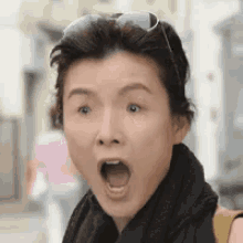 a woman wearing sunglasses and a scarf is making a funny face .