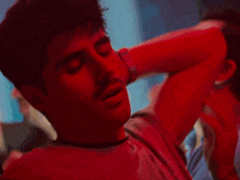 a man in a red shirt is dancing in a dark room