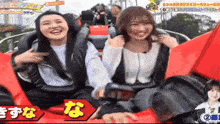 two women are riding a roller coaster with chinese writing on the bottom right