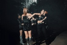 a group of women are dancing in a dark room with trees in the background
