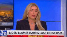 a woman is sitting in front of a fox news breaking news sign .