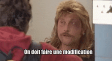 a man with a mullet and a mustache is talking to another man with the words on doit faire une modification above him