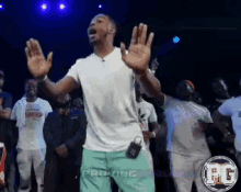 a man in a white shirt and green shorts is standing in front of a crowd with the letters fg on the bottom