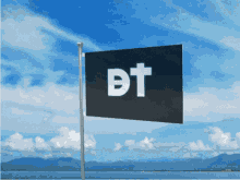a black flag with the letter dt on it is flying in the wind